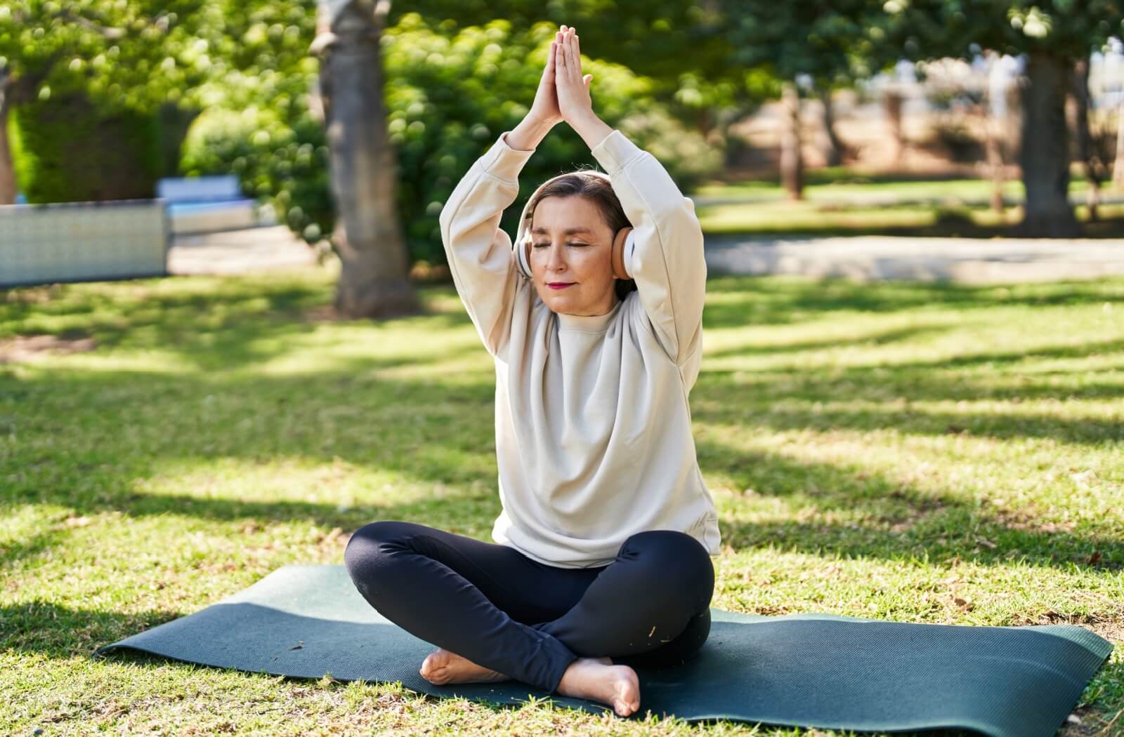 An older adult practices yoga outdoors.