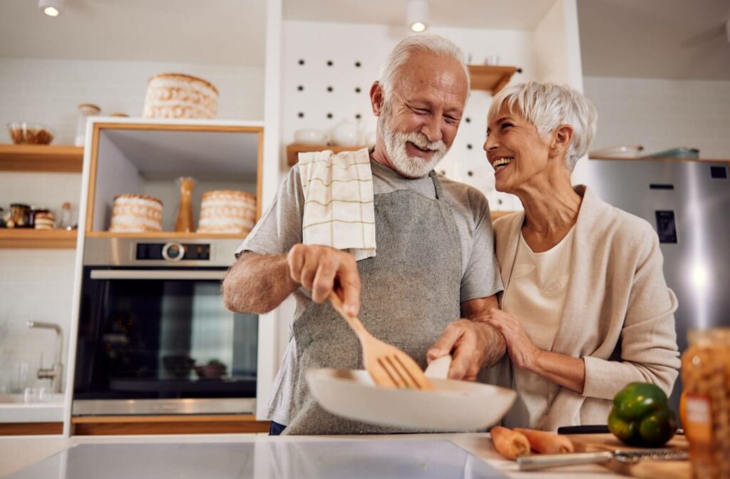 A happy older adult couple cook together.