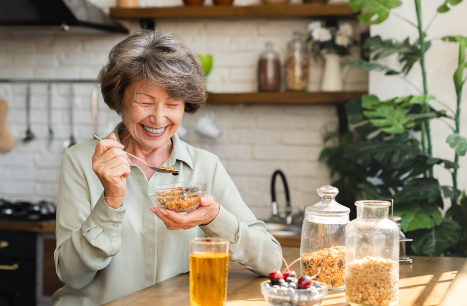 Senior woman enjoying a protein-rich granola meal in a bright kitchen.