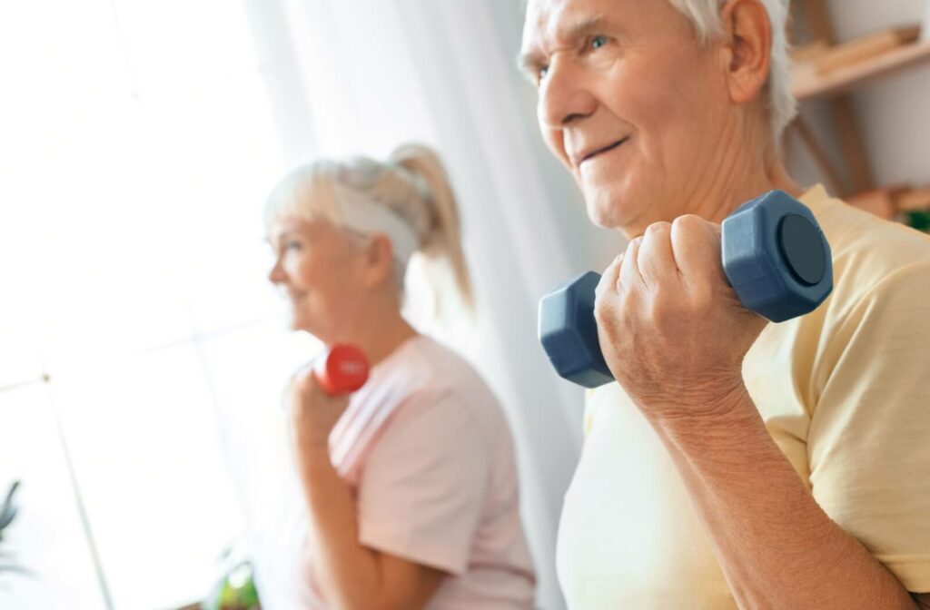 An older married couple using small handheld weights during a strength training exercise class.