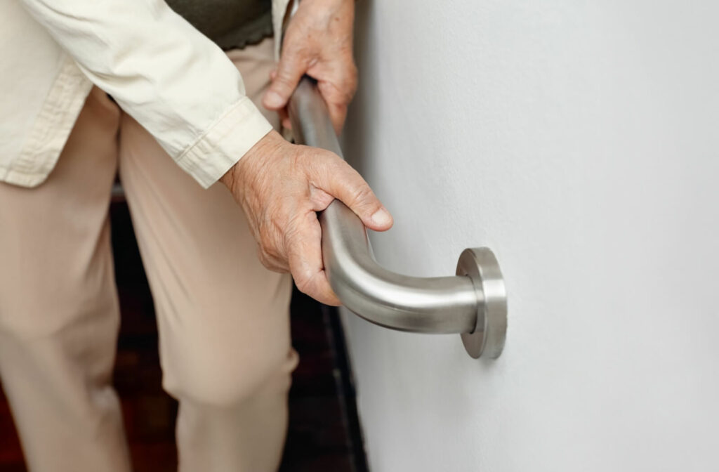 An older adult with dementia using a handrail to safely go down the stairs in their home.