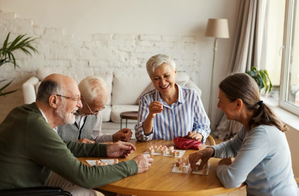 A group of older adults in senior living playing a board game together and laughing.

