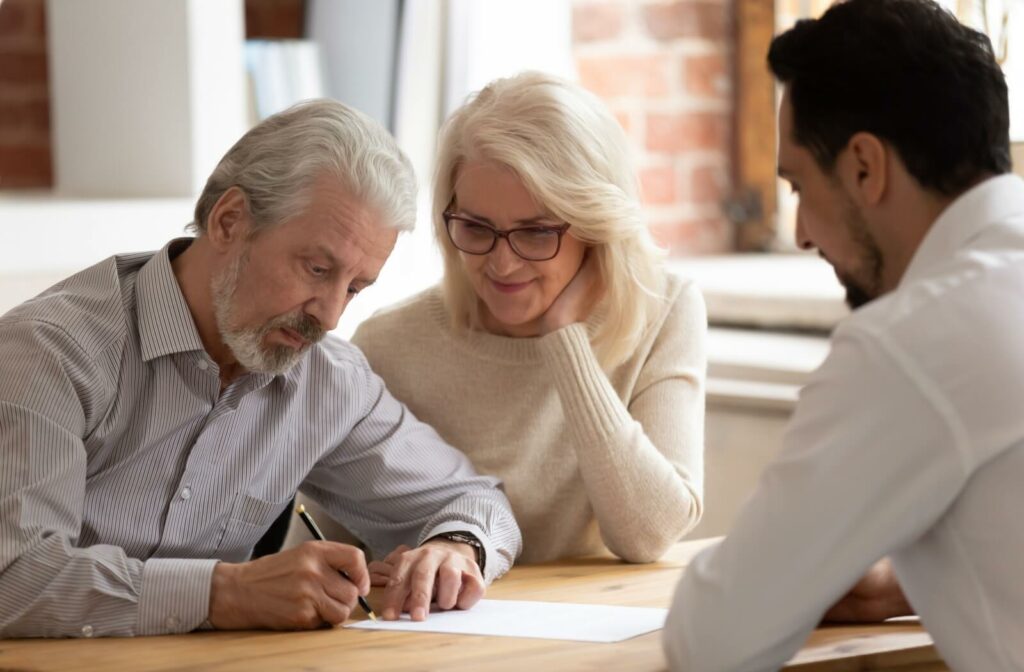An older couple smiling while doing paperwork to prepare for a move to assisted living.