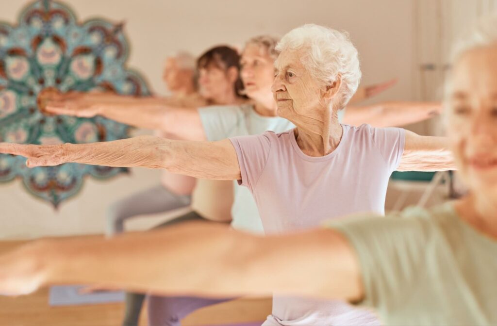 Five older adults do yoga during a group exercise class in senior living