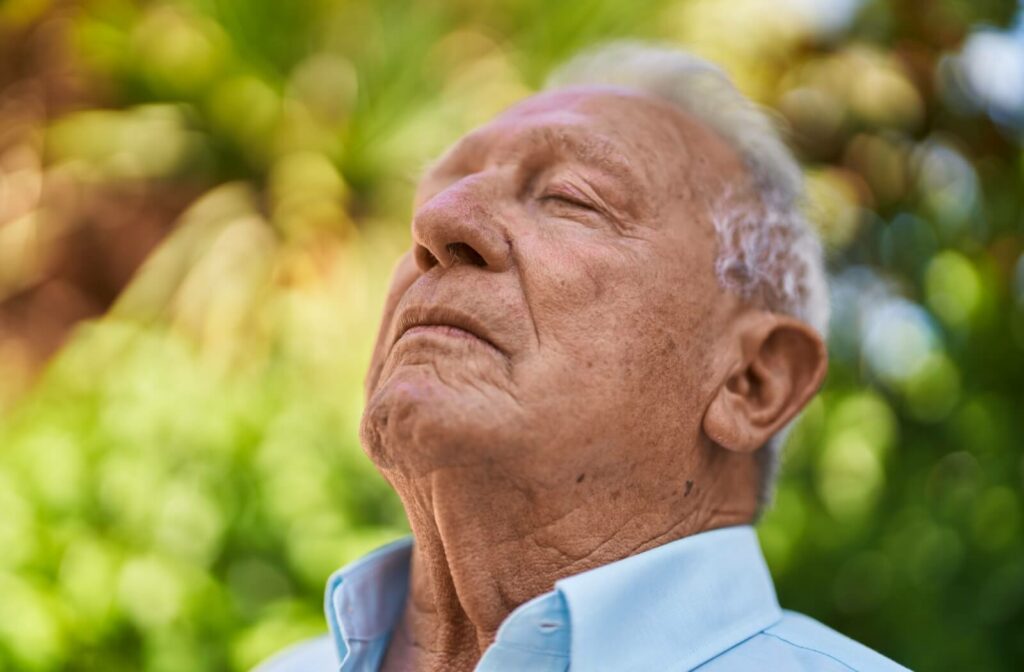 An older adult pauses on a walk outdoors to close their eyes and ground themselves during a short meditation