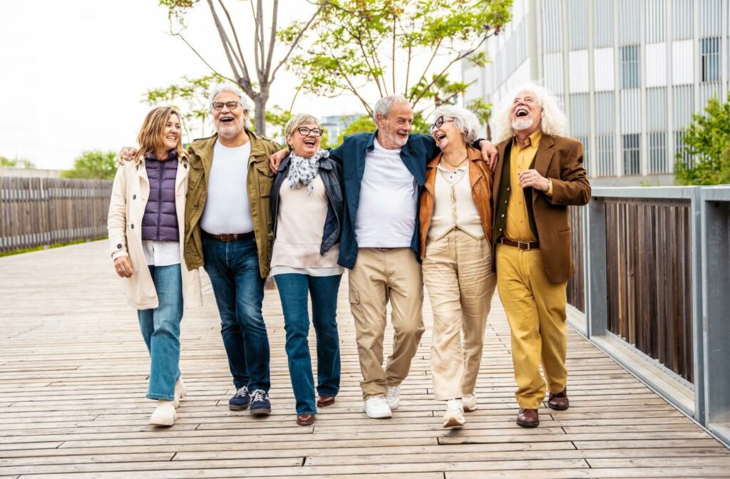 A group of older adults walk with arms around one another across a bridge downtown during a group outing