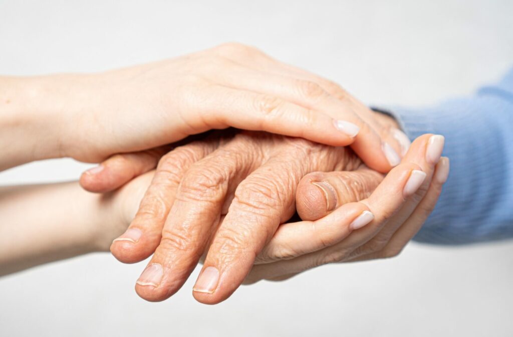 Close up of a caregiver holdings an older adult's hand.