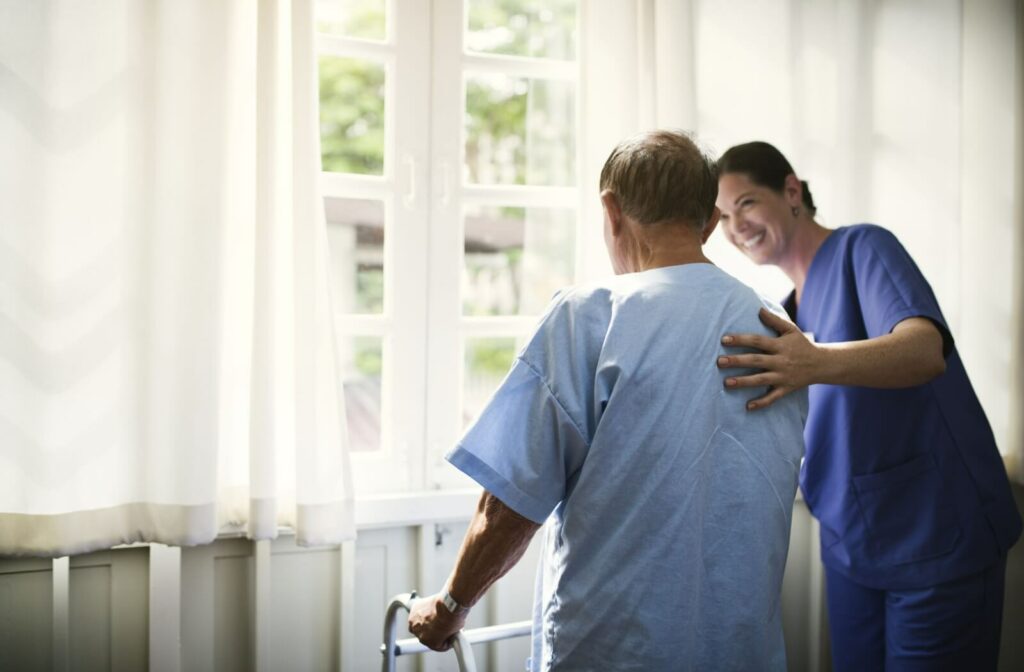 A nurse guides someone towards the window in the morning.