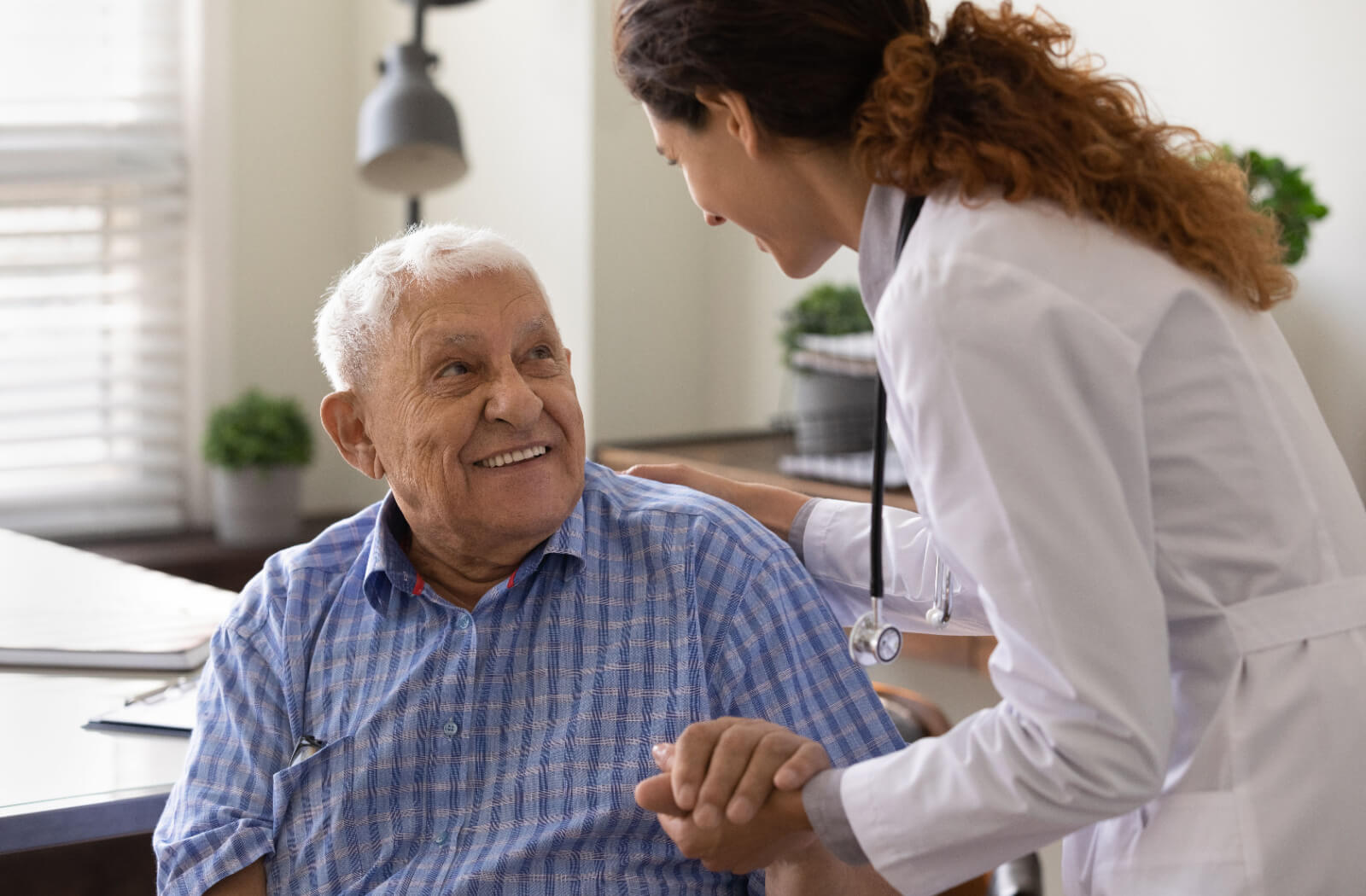 A nurse checking on a smiling resident in assisted living during a regular healthcare checkup.